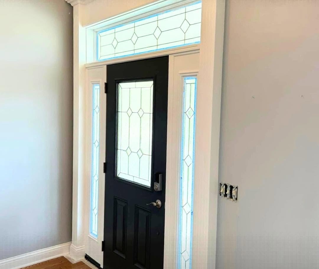 Entryway with a black front door and stained-glass sidelights