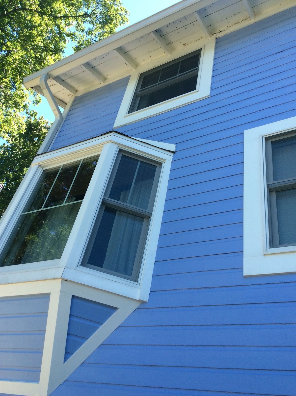 Blue home with white bay window trim repainted