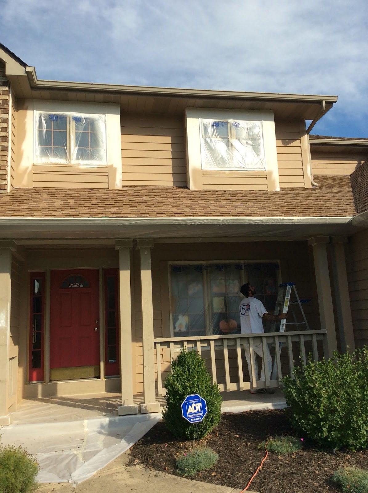 Two-storey home with a red front door being repainted
